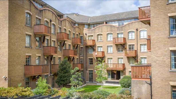 A multi-story residential building with balconies, a central courtyard, and surrounding greenery. - London Tower Bridge Apartments (London)