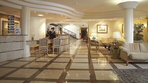 Un vestíbulo amplio con mostrador de recepción, zona de estar y una escalera que conduce a los pisos superiores.