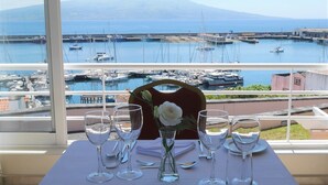 Mesa lista para comer con vista a un puerto deportivo y una montaña al fondo.