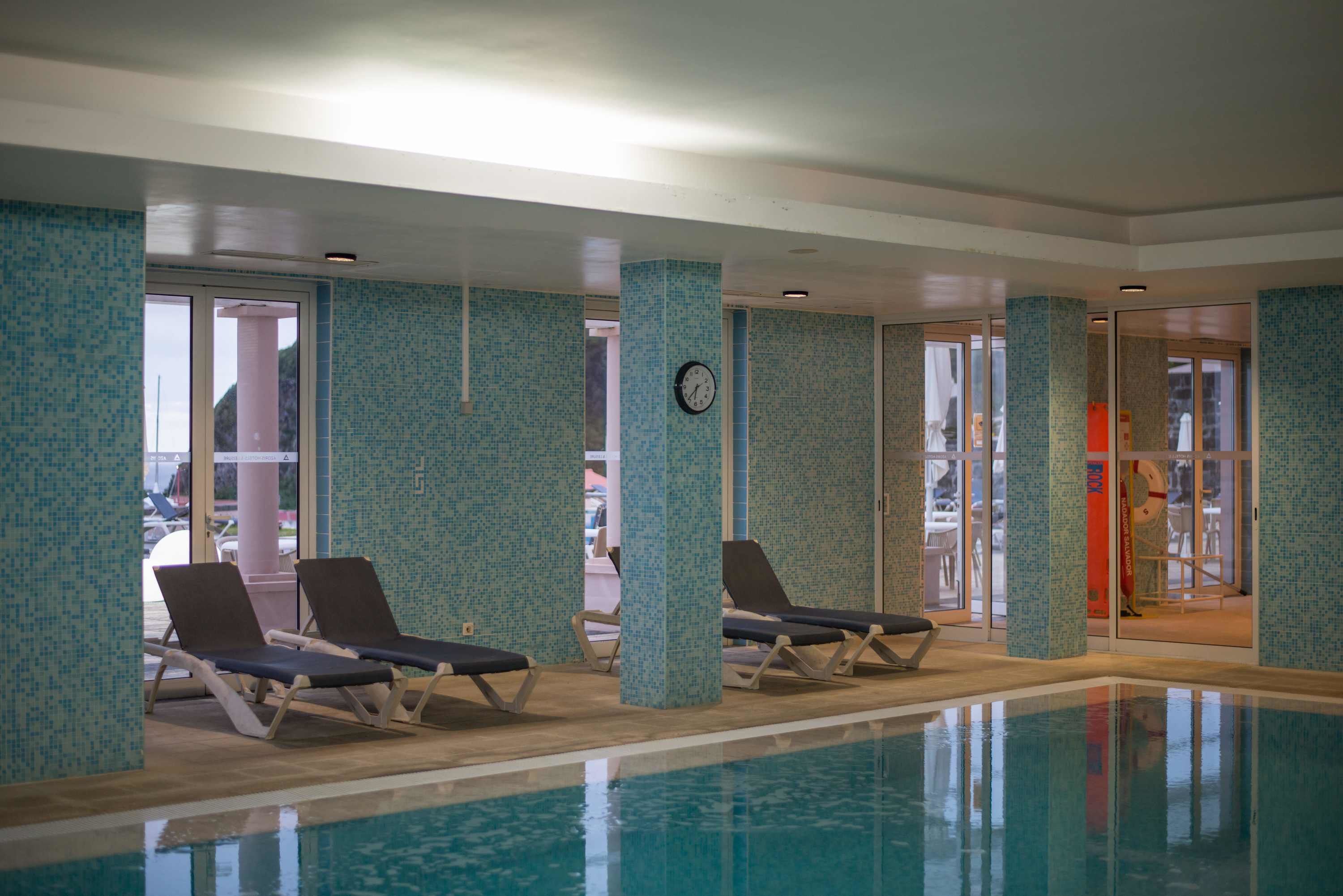 An indoor swimming pool with tiled walls and ceiling, surrounded by lounge chairs.