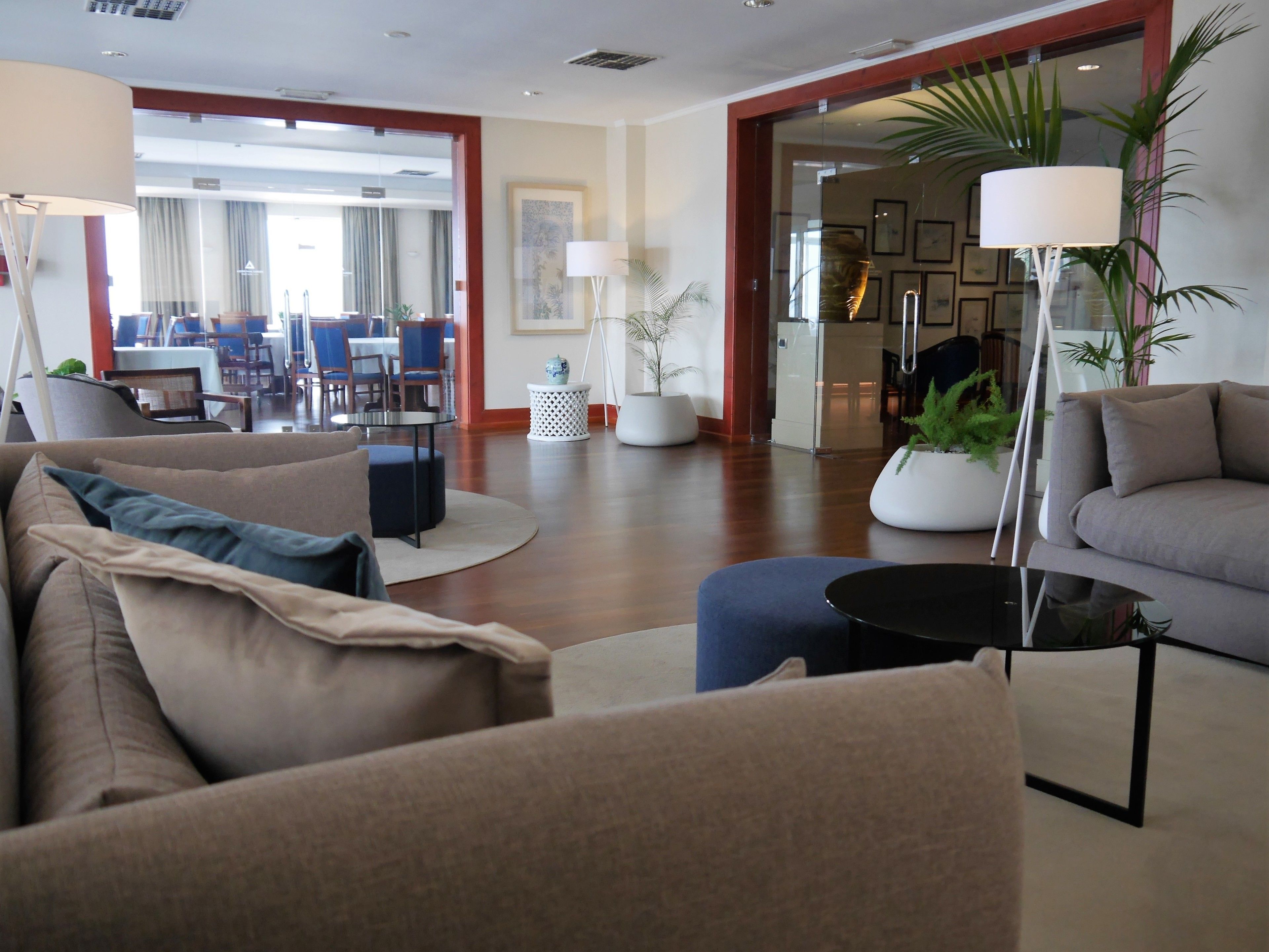 A modern hotel lobby with a seating area, a dining area, and a reception desk.