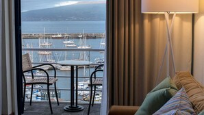 Un balcón con vista a un puerto deportivo, una silla colgante y una mesa con sillas.