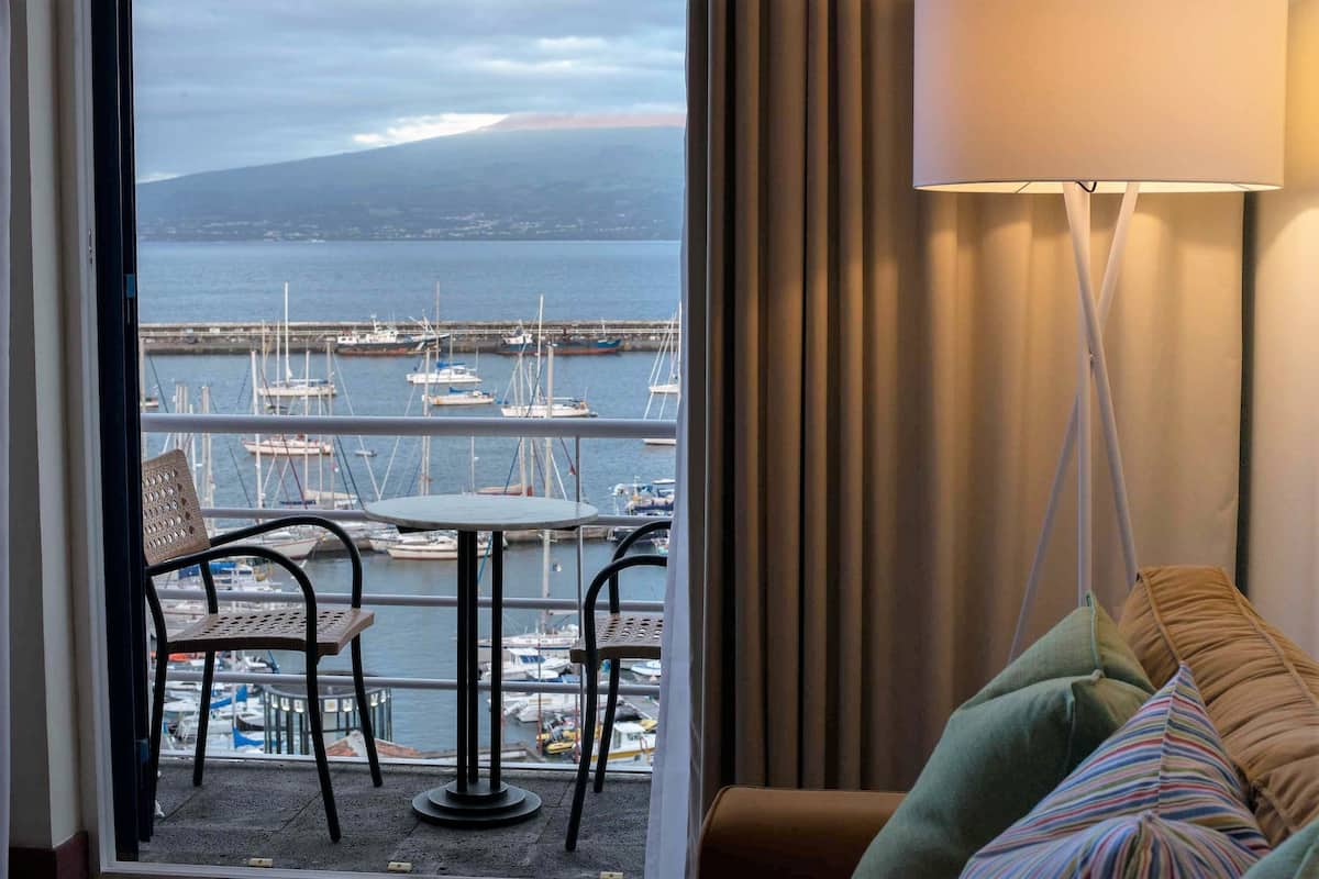 A balcony with a view of a marina, a hanging chair, and a table with chairs.