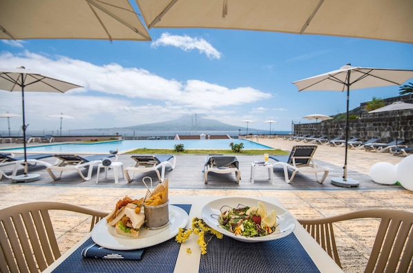 Alberca techada, alberca al aire libre y sombrillas en la alberca