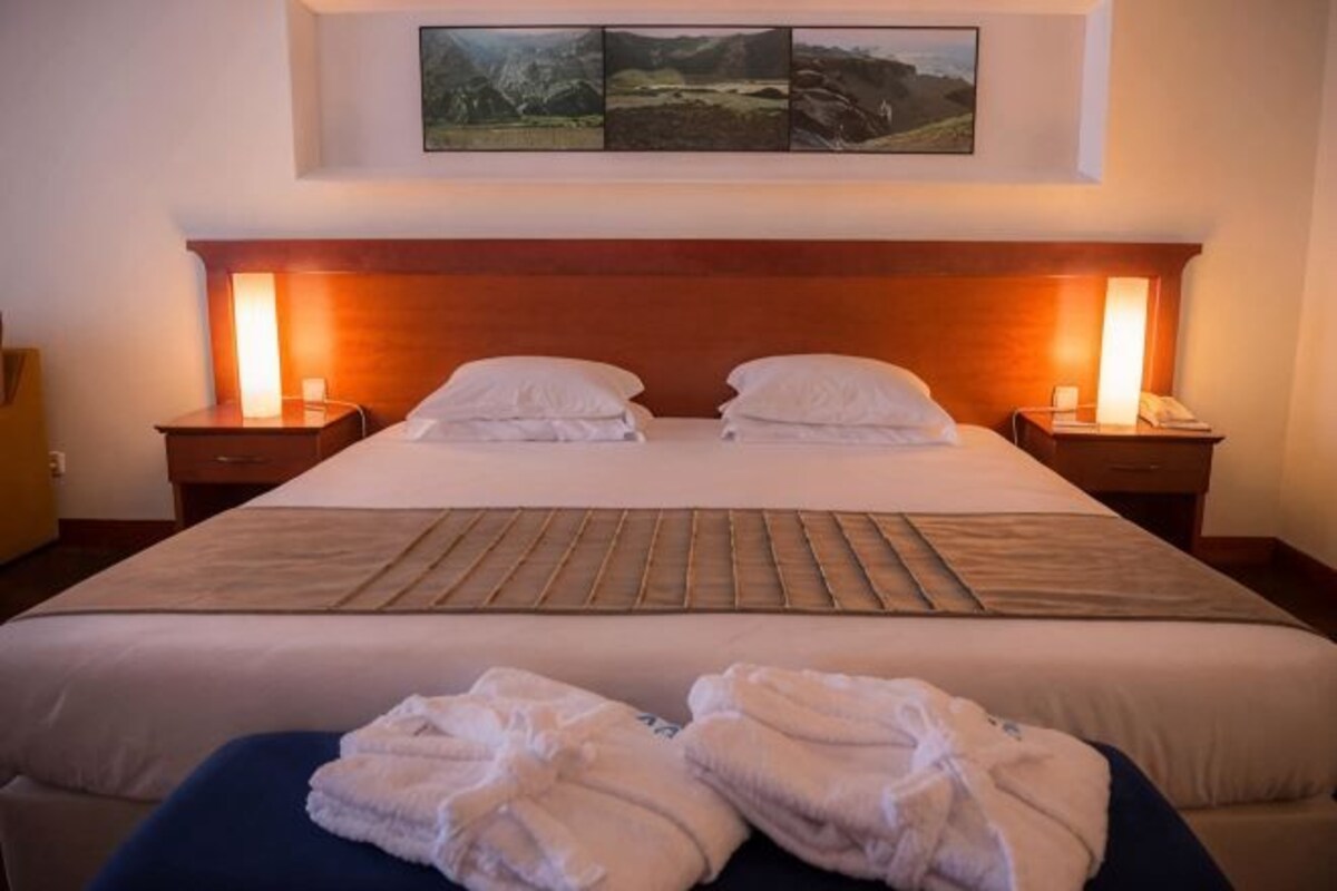 Ein Hotelzimmer mit einem großen Bett, zwei Nachttischen und einer Kopfteil.