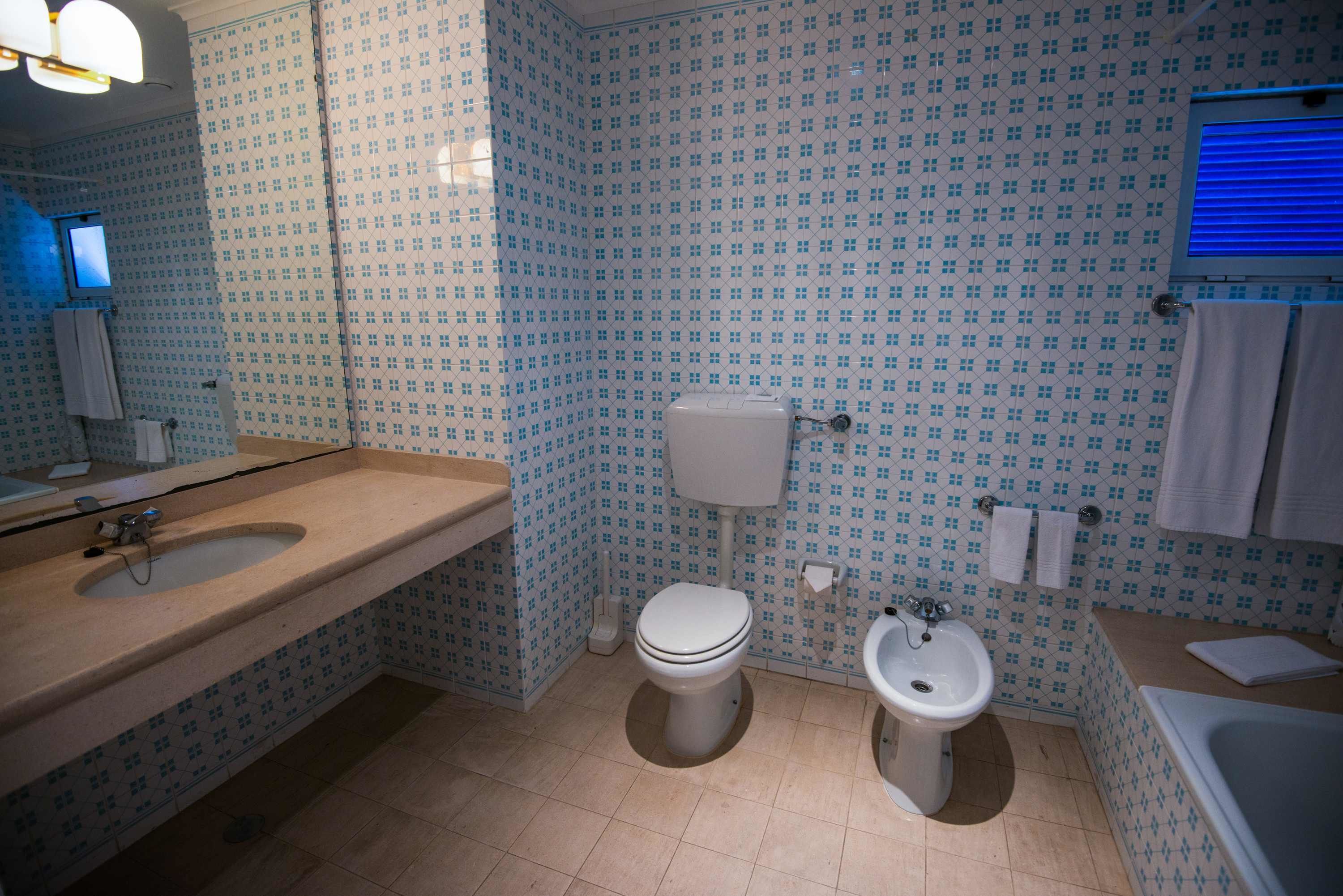 A bathroom with a sink, toilet, bidet, and bathtub.