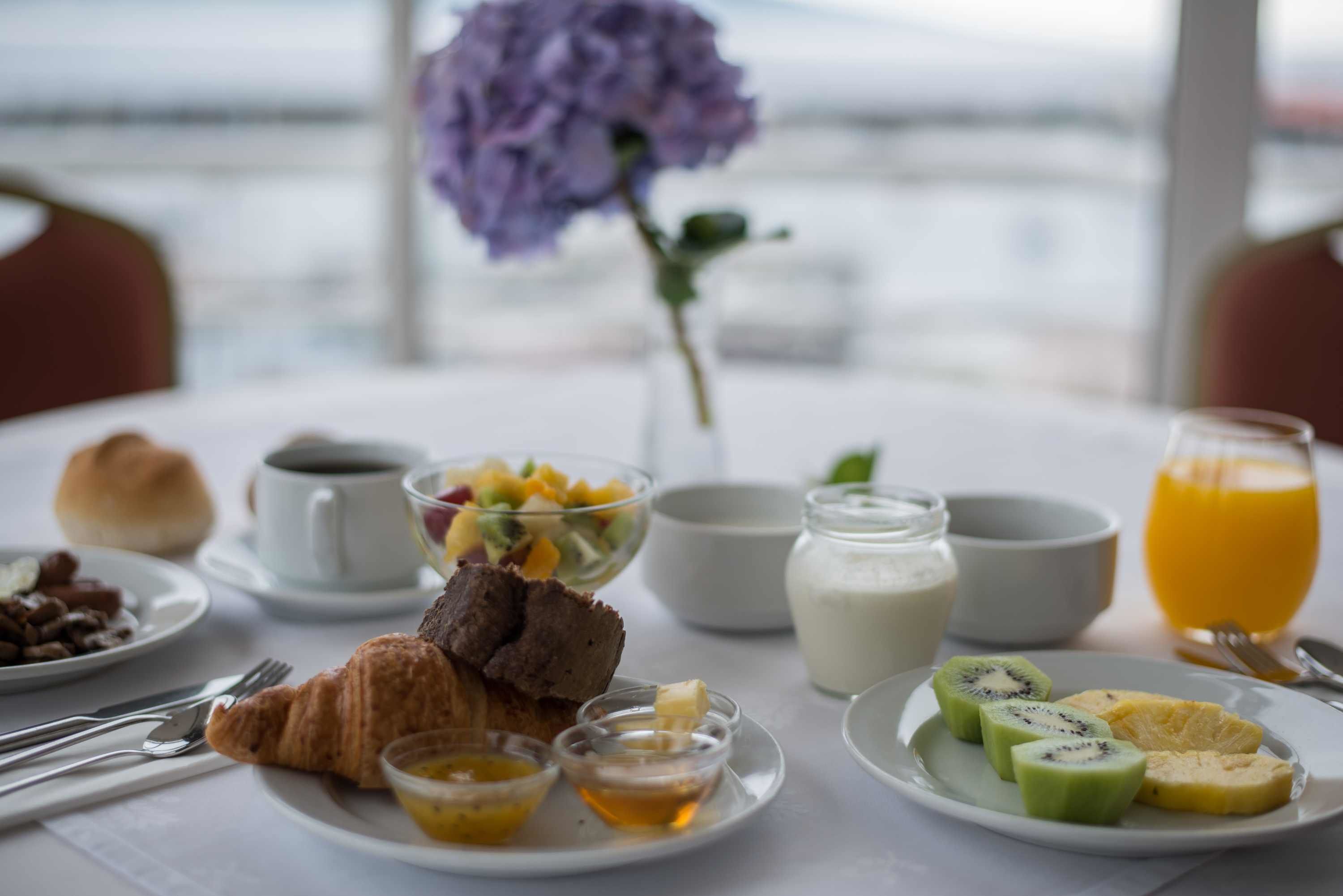 A breakfast table with croissants, fruit, and beverages.