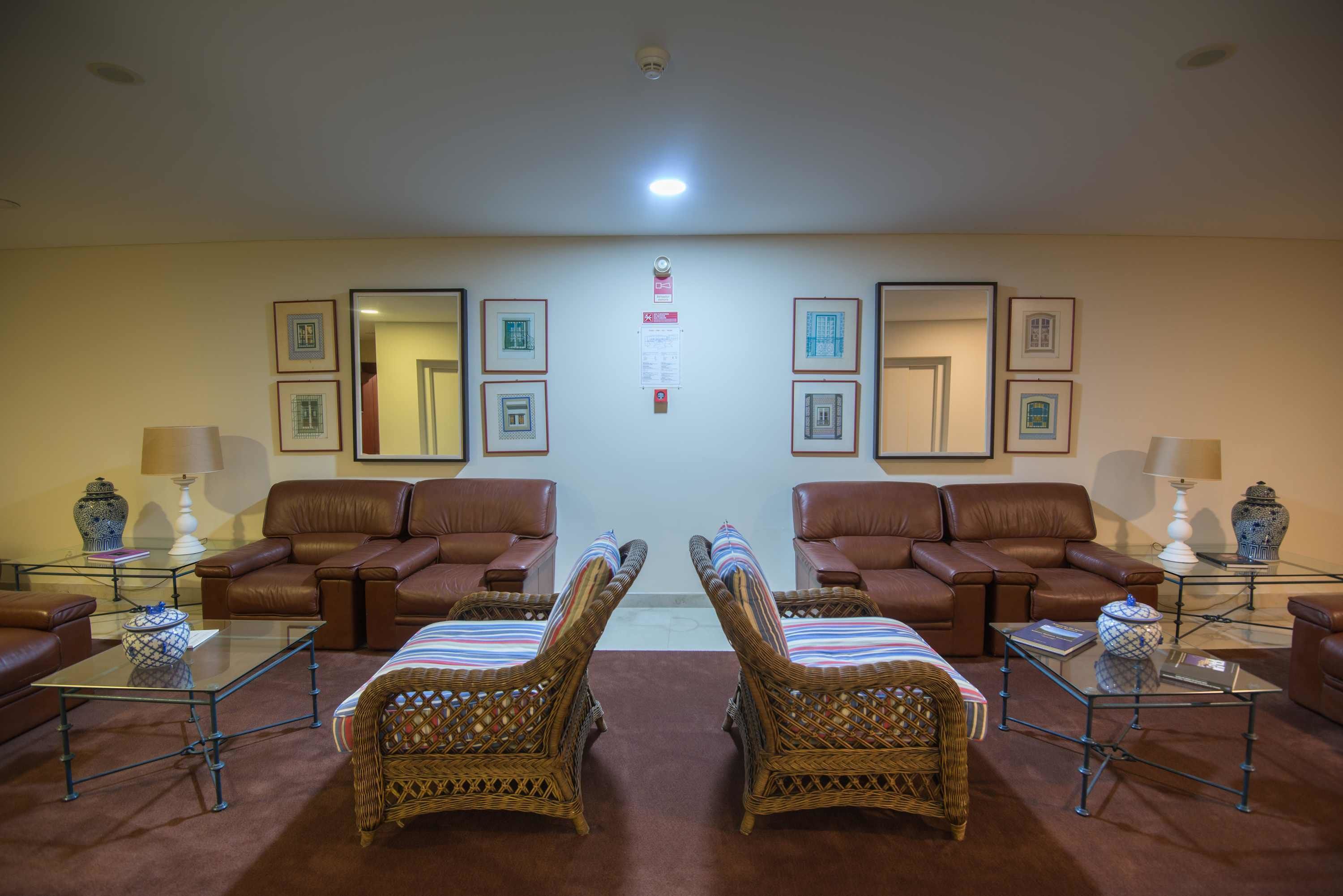 Un hall de hotel con sofás de cuero marrón, sillas de mimbre y mesas de centro de vidrio.