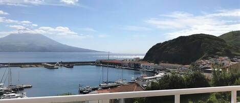Un pueblo costero con un puerto deportivo, edificios y una montaña al fondo.