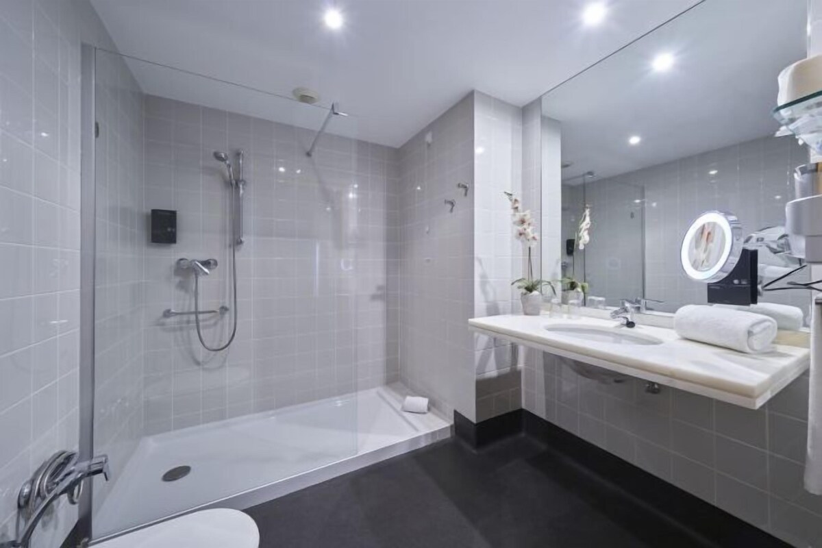 A modern bathroom with a glass-enclosed shower, a vanity with a mirror, and a toilet.