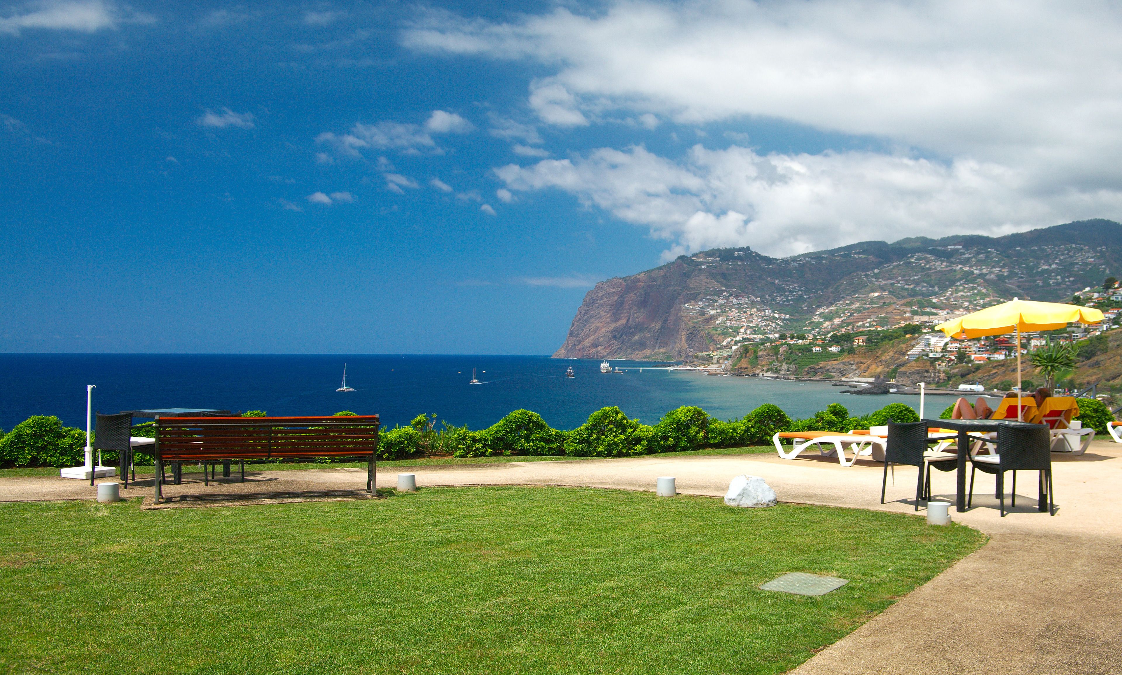 Une vue sur la côte avec un banc, des tables et des parasols.