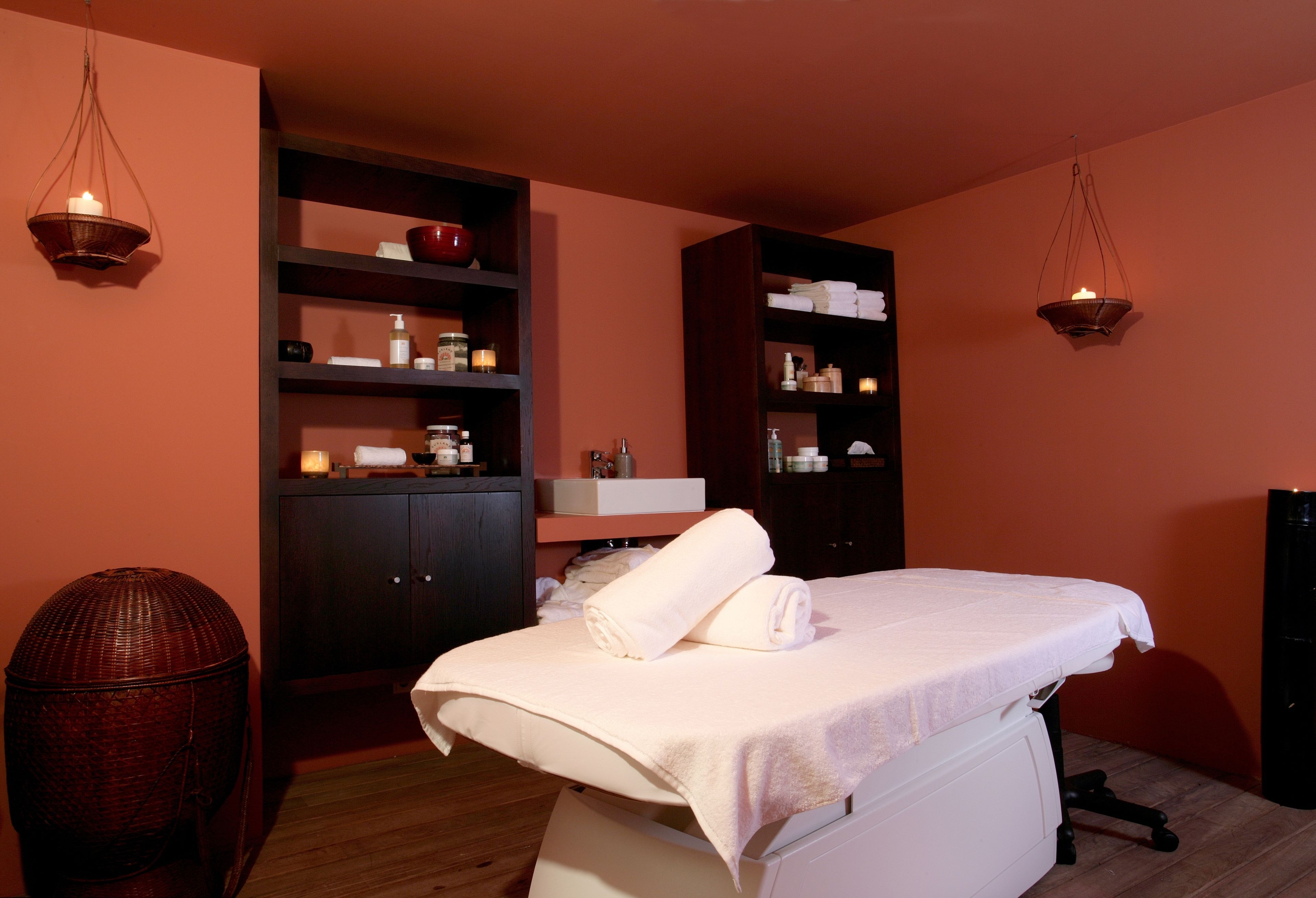 Una habitación con cama, repisas con artículos de aseo personal y una cesta de mimbre.