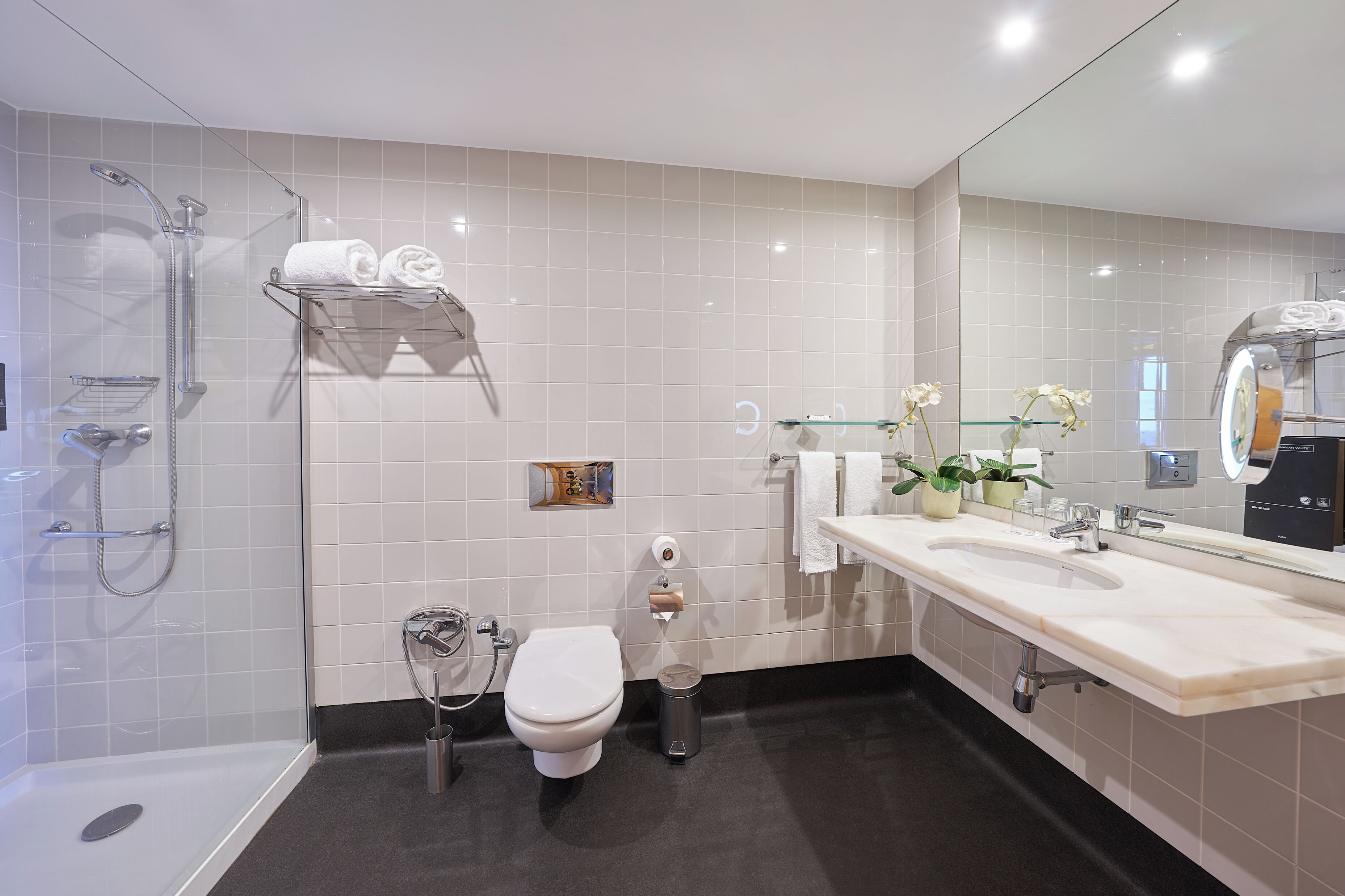 A modern bathroom with a shower, toilet, and sink.