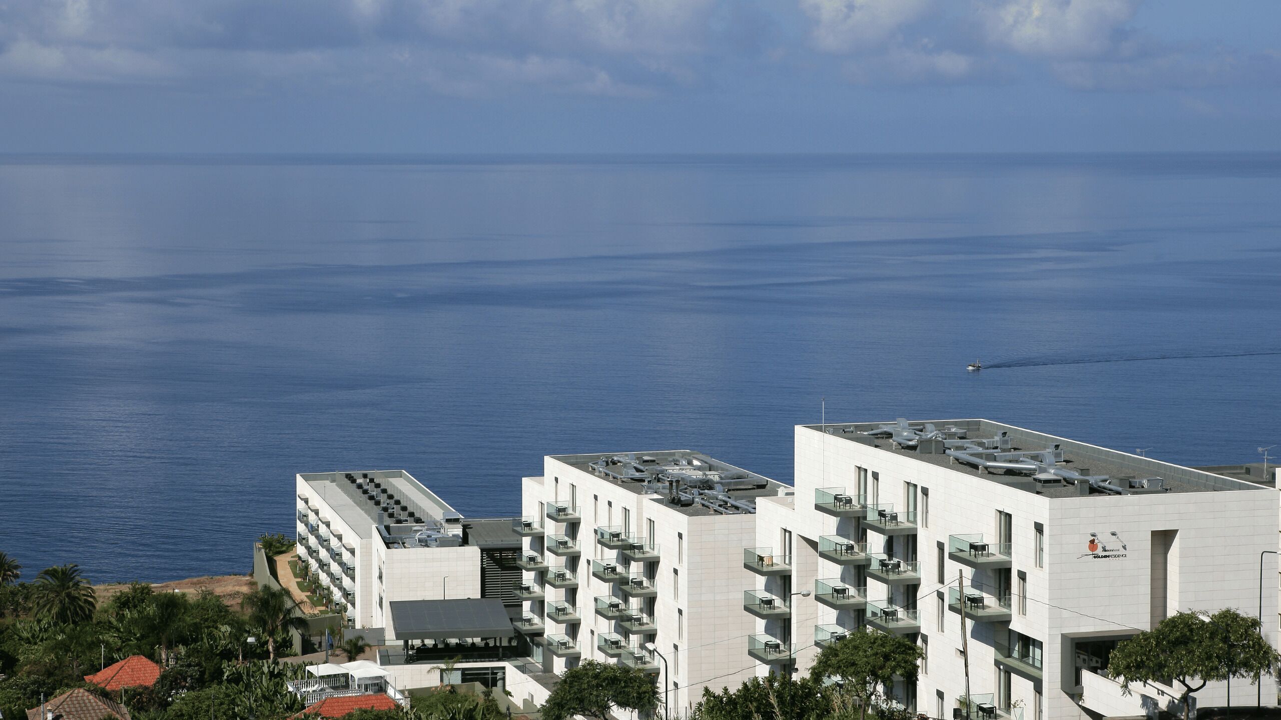 Un hôtel moderne à plusieurs étages, doté de balcons et offrant une vue sur la mer.