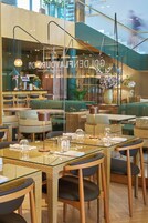 A restaurant with glass tables and chairs, a staircase in the background, and a sign reading "GOLDEN LOOK".