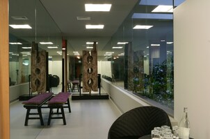 Un interior moderno con divisiones de vidrio, obras de arte de madera y vistas a zonas verdes exteriores.