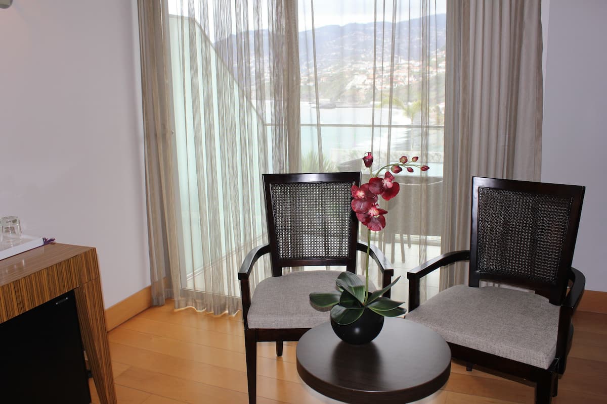 A room with two chairs, a small table, and a view through sheer curtains.