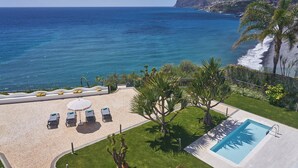 A pool area with a view of the ocean, a beach, and a mountain in the background. - Golden Residence Hotel (Funchal)