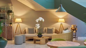 A modern living room with a sofa, two lamps, a teddy bear, and a staircase in the background. - Golden Residence Hotel (Funchal)