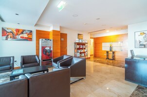 A modern lobby with leather seating, a reception desk, and a bookshelf.