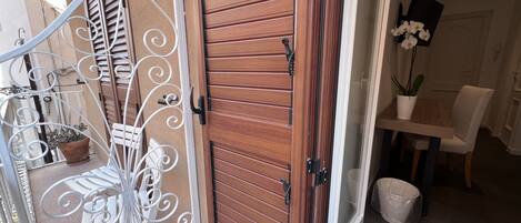 Une porte en bois avec un portail en métal, une plante en pot et un coin repas avec une table et des chaises.