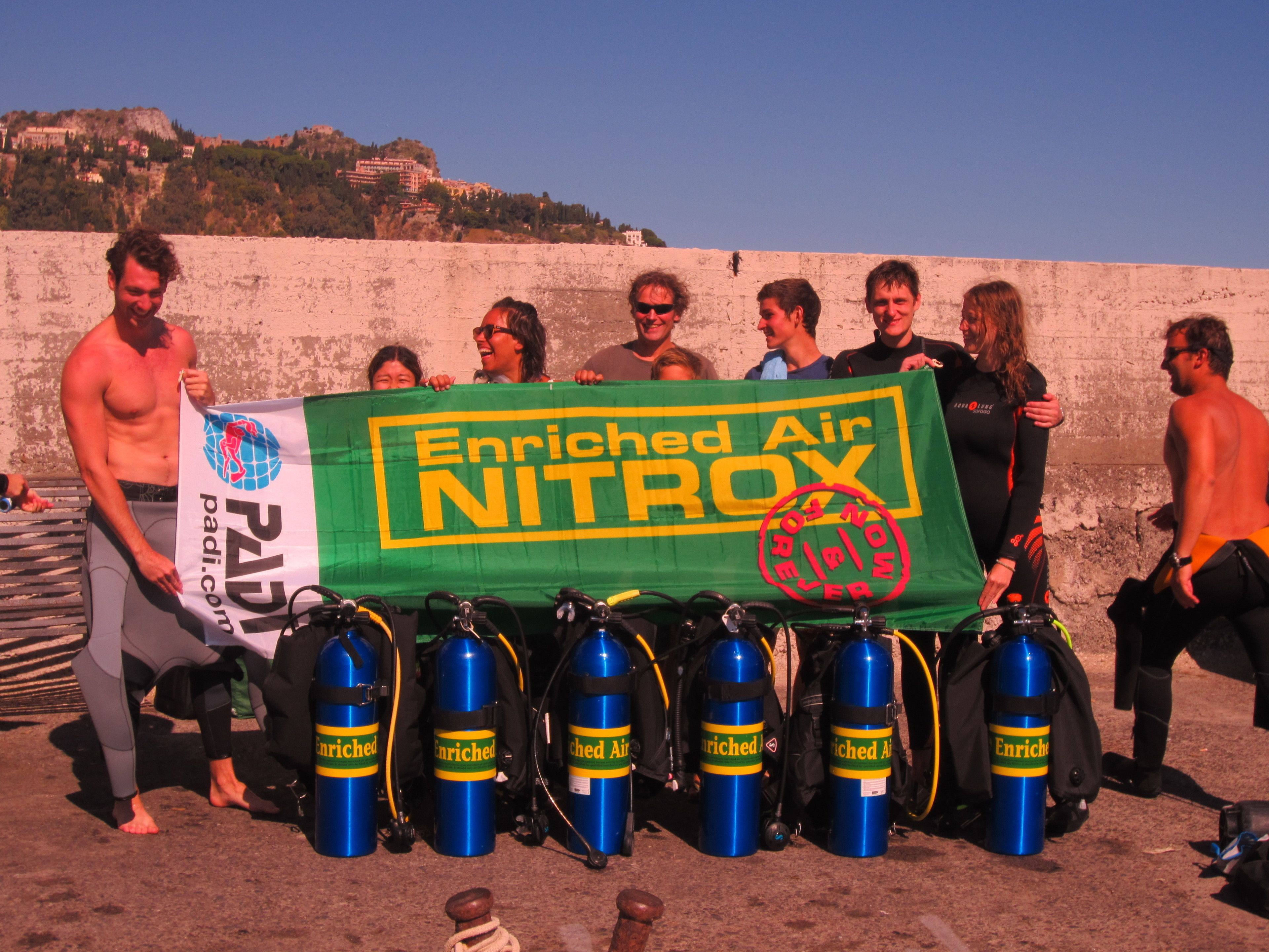 A group of people holding a banner and several blue air tanks.