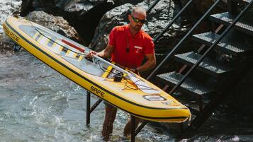 Un uomo con una camicia rossa che tiene in mano un kayak giallo con la scritta "SAFE".