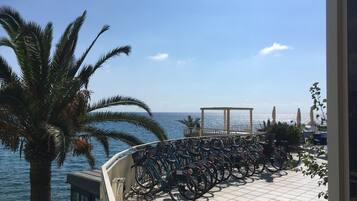 Un balcón con bicicletas, una palmera y vista al mar.