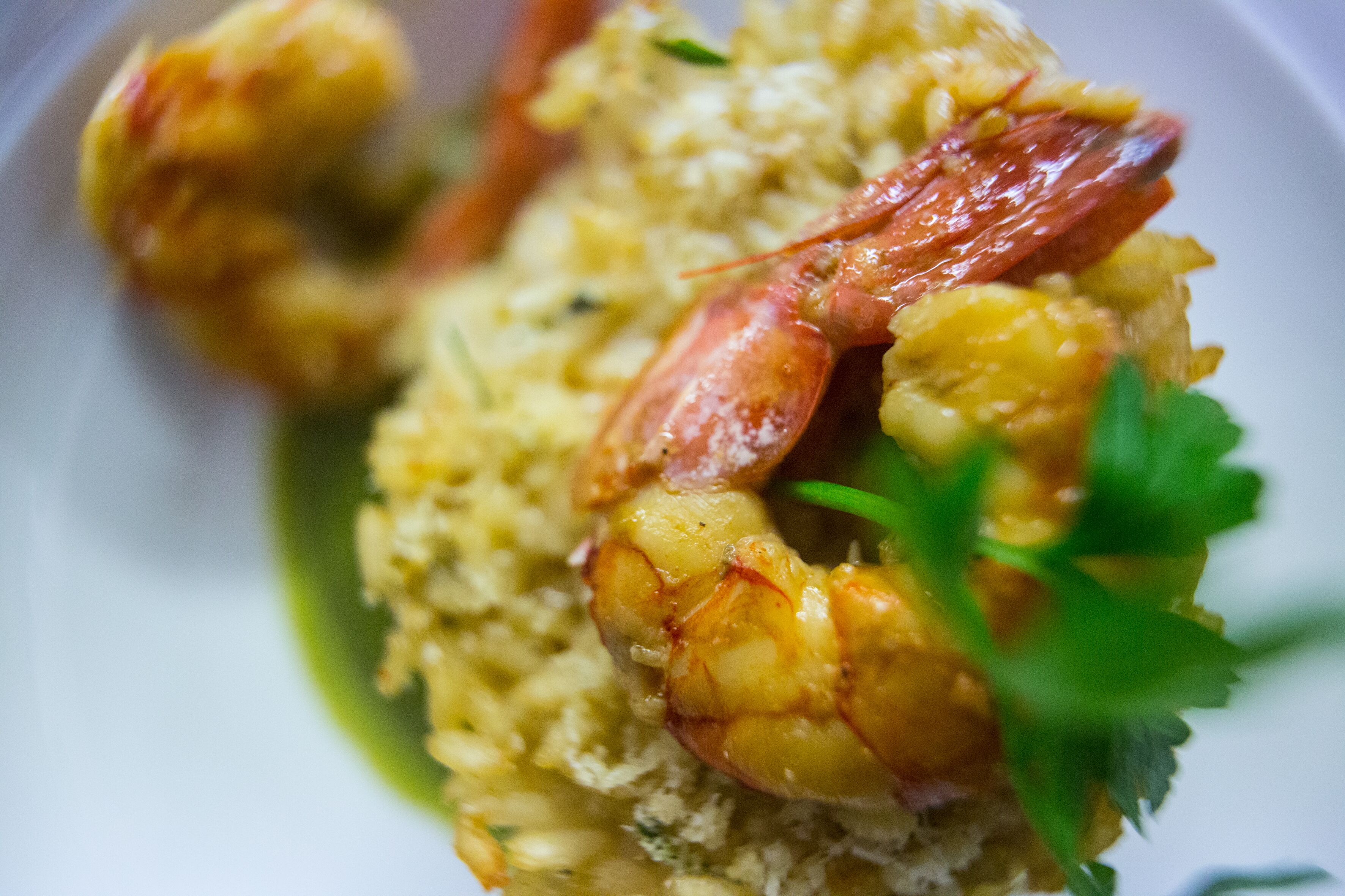 Une assiette de nourriture contenant des crevettes et du riz, le tout garni de persil.
