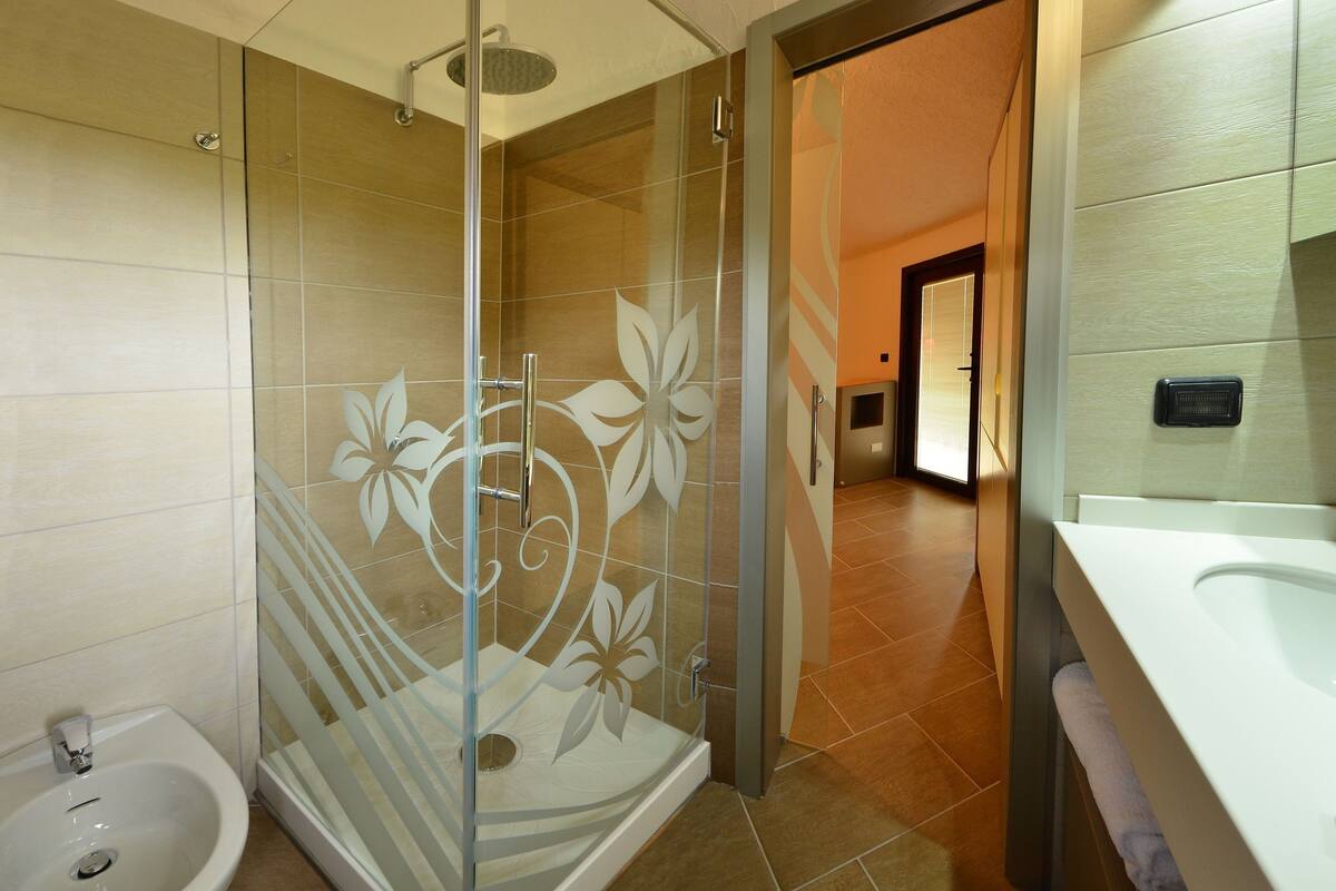 A modern bathroom with a glass-enclosed shower, a sink, and a mirror.