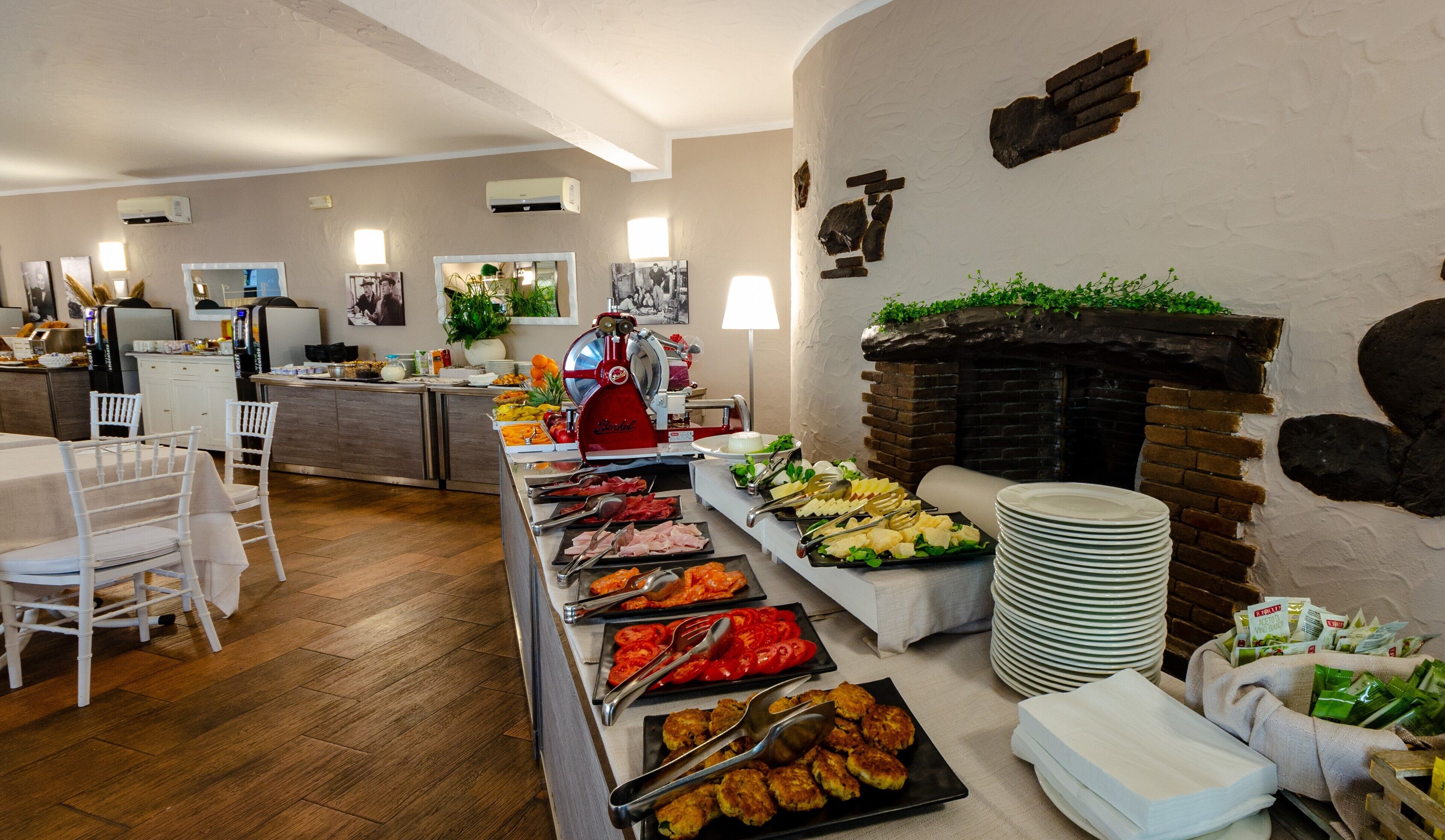 Montaje tipo bufé con diversos alimentos, una parrilla y disposición de mesas en un comedor.