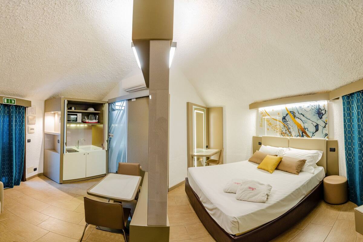 A hotel room with a bed, a sofa, a small table, a desk, and a bathroom.