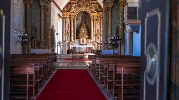 L’intérieur d’une église, avec des rangées de bancs en bois, une moquette rouge et un autel richement décoré.
