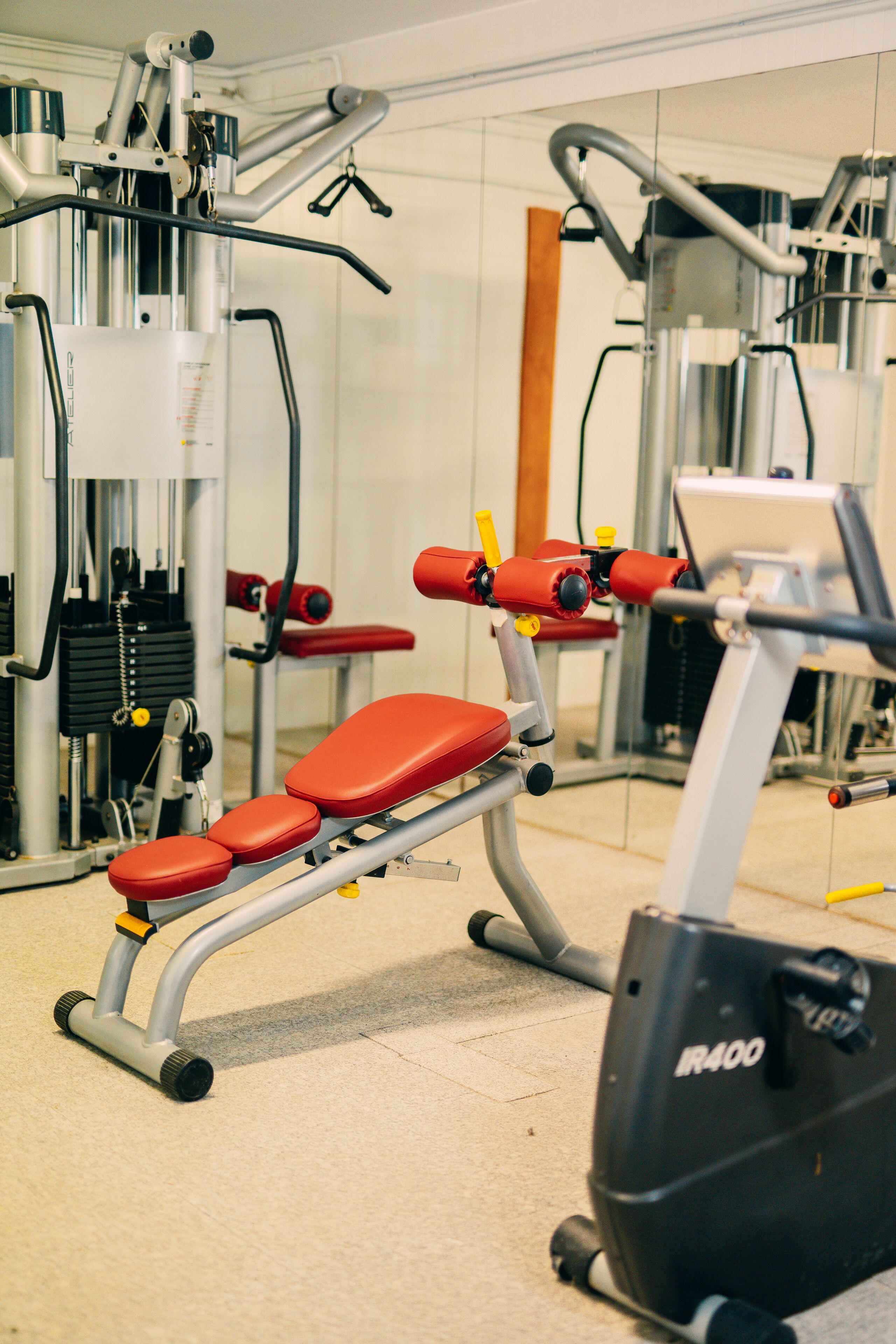 Un gimnasio con equipo de ejercicio, incluyendo una banca y una bicicleta estática.