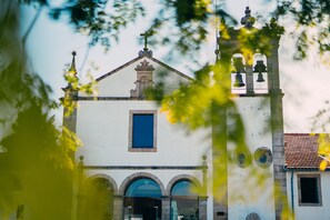 A church with a bell tower, arched windows, and a clock. - Forte de São Francisco Hotel (Chaves)