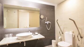 Un baño moderno con un espejo grande, un lavabo y un inodoro.