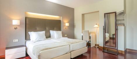 A modern hotel room with a large bed, bedside lamps, and a mirror.