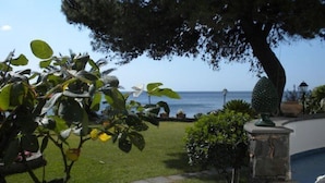 A garden with a view of the sea, a stone bench, and a pineapple statue. - Arathena Rocks Hotel (Giardini Naxos)
