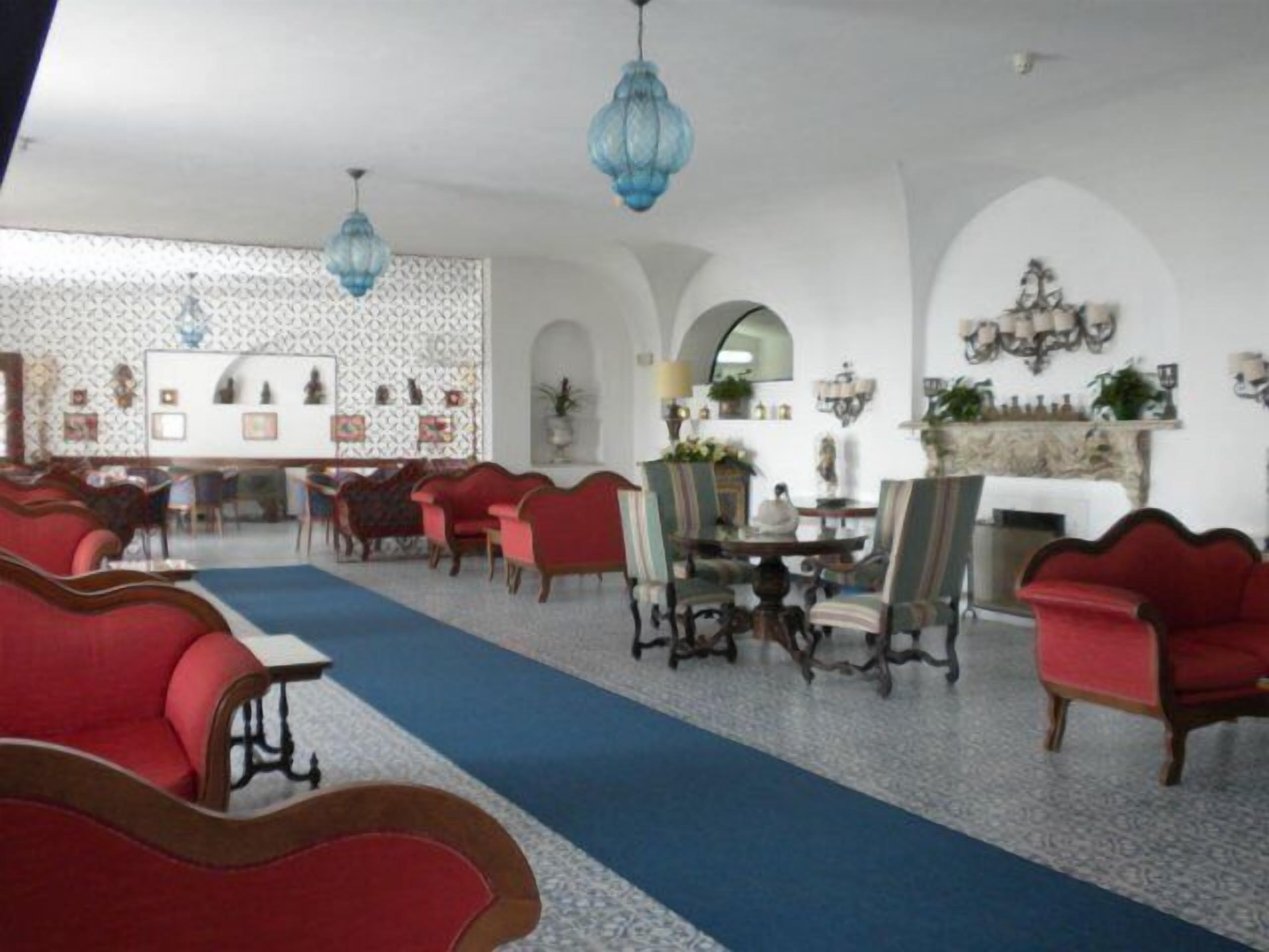 A dining area with red upholstered chairs, a blue carpet, and blue hanging lamps.
