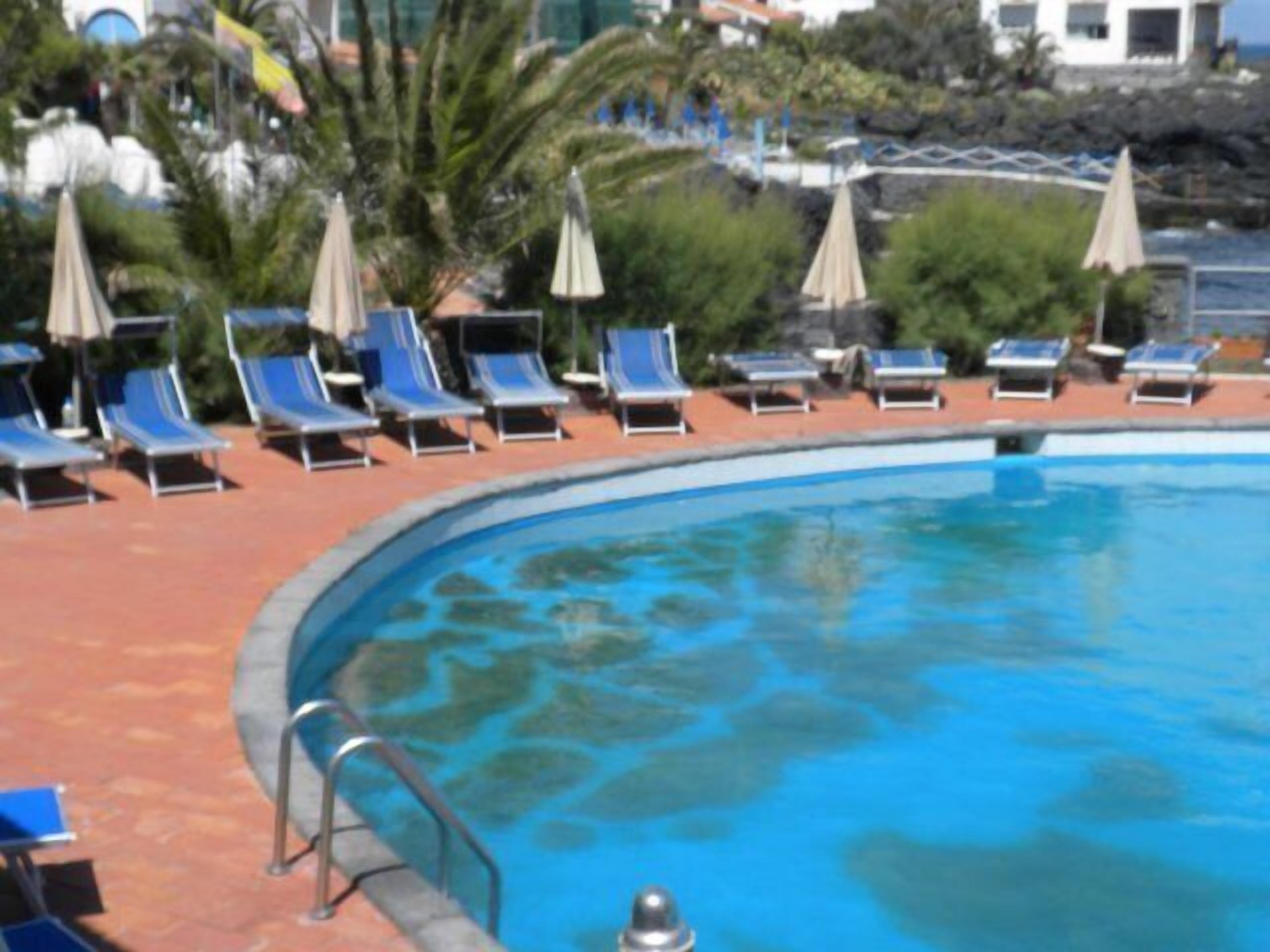 A swimming pool with blue lounge chairs and umbrellas around it.