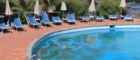 A swimming pool with blue lounge chairs and umbrellas around it.