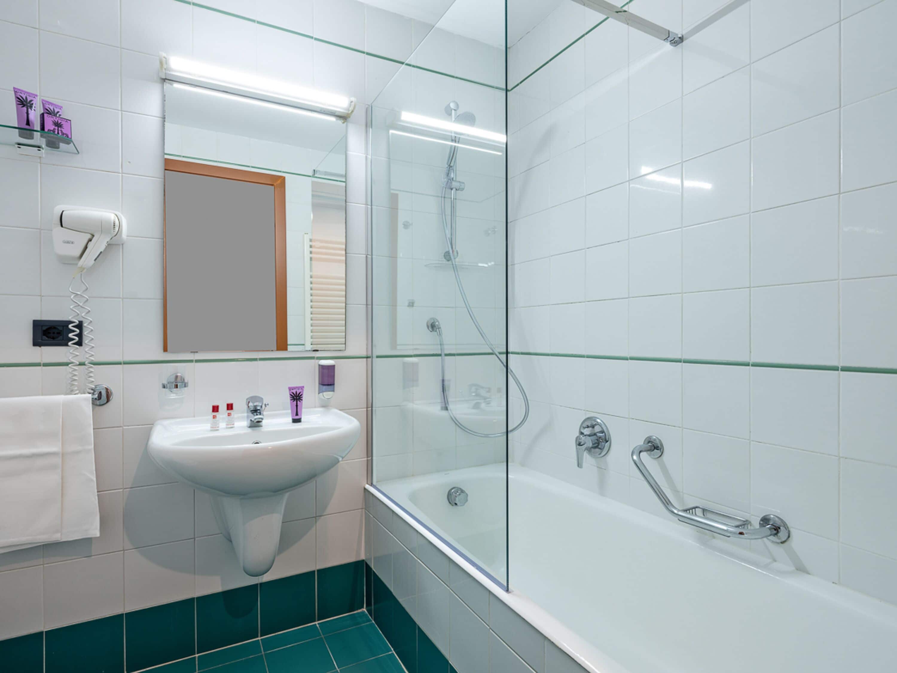 A modern bathroom with a glass shower enclosure, a white sink, and a bathtub.