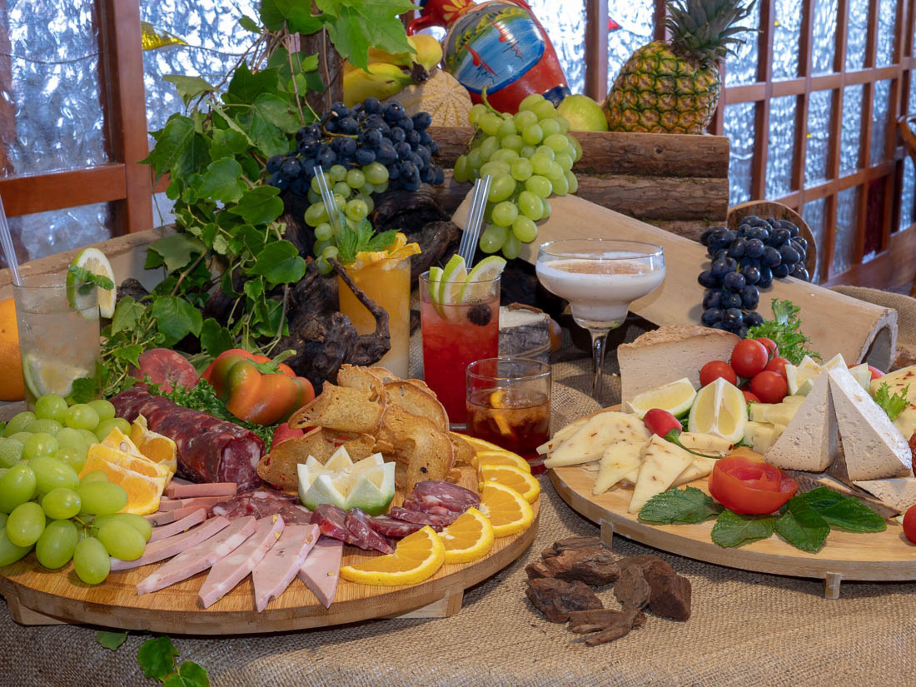 A charcuterie board with various meats, cheeses, fruits, and a drink.