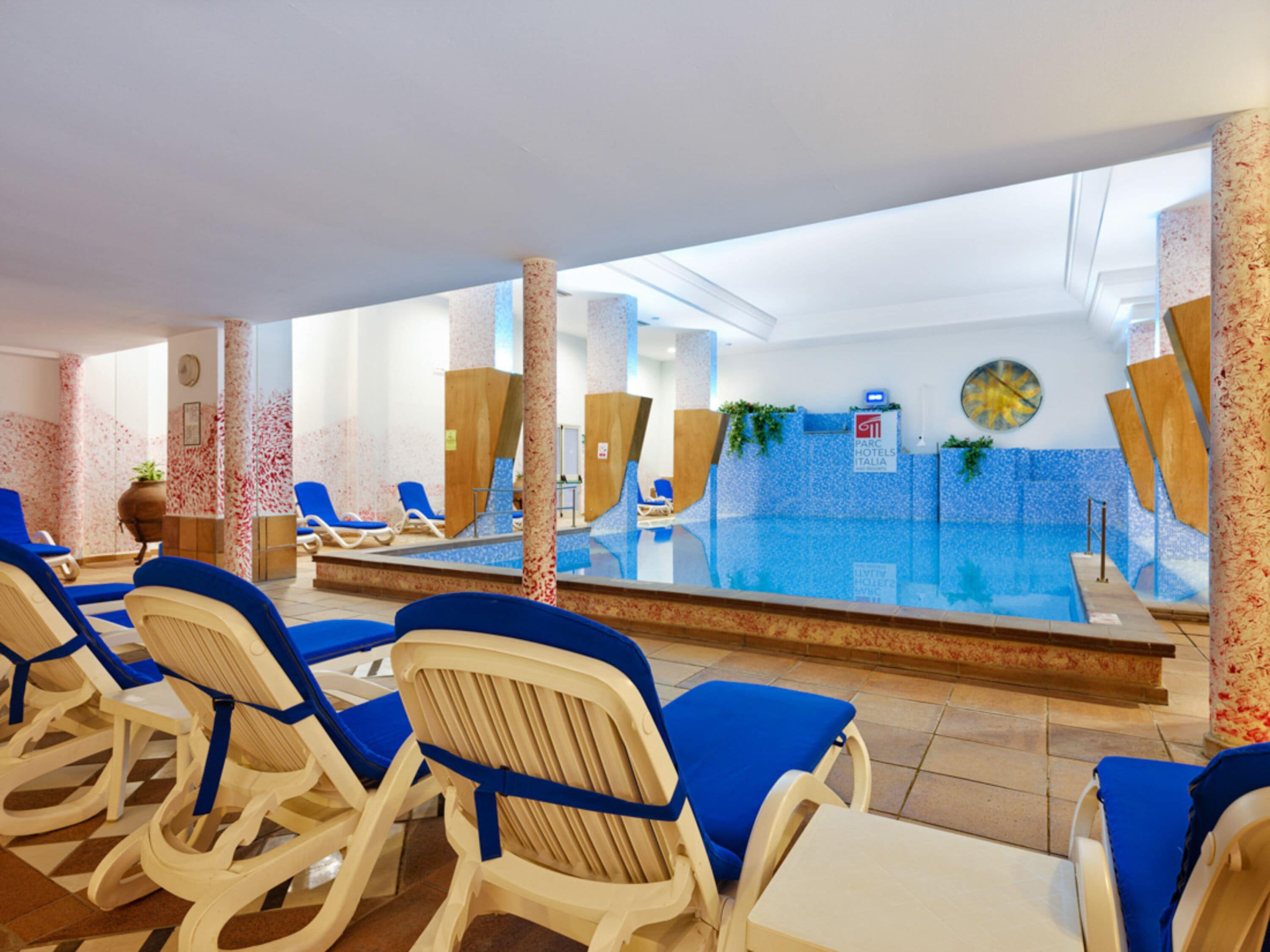 Zona de piscina con sillas reclinables azules y vista despejada al agua.