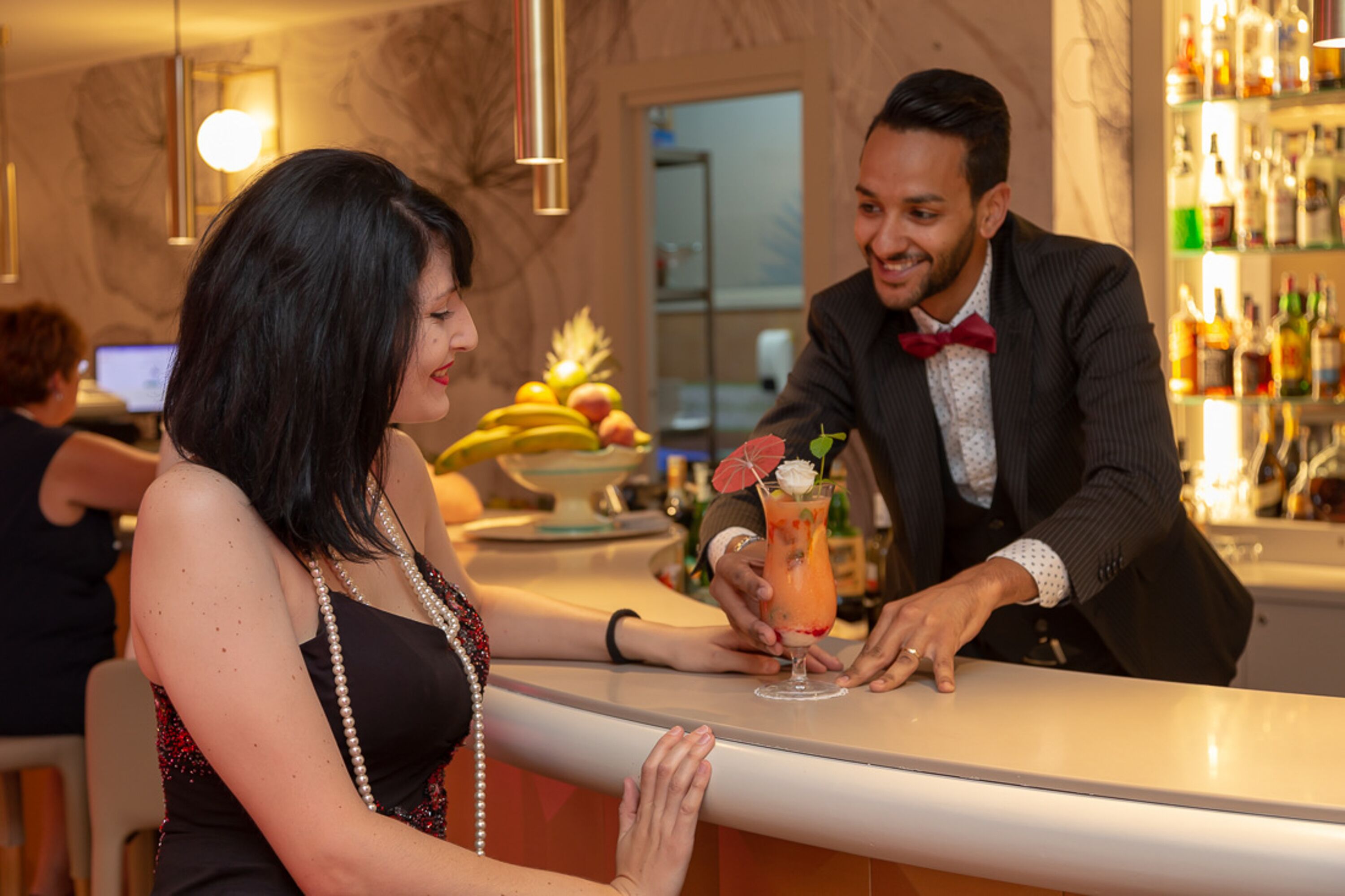Un coin bar où un barman prépare un cocktail pour une femme.
