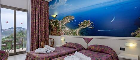 A hotel room with two beds, a balcony, and a large scenic mural of a coastal landscape.
