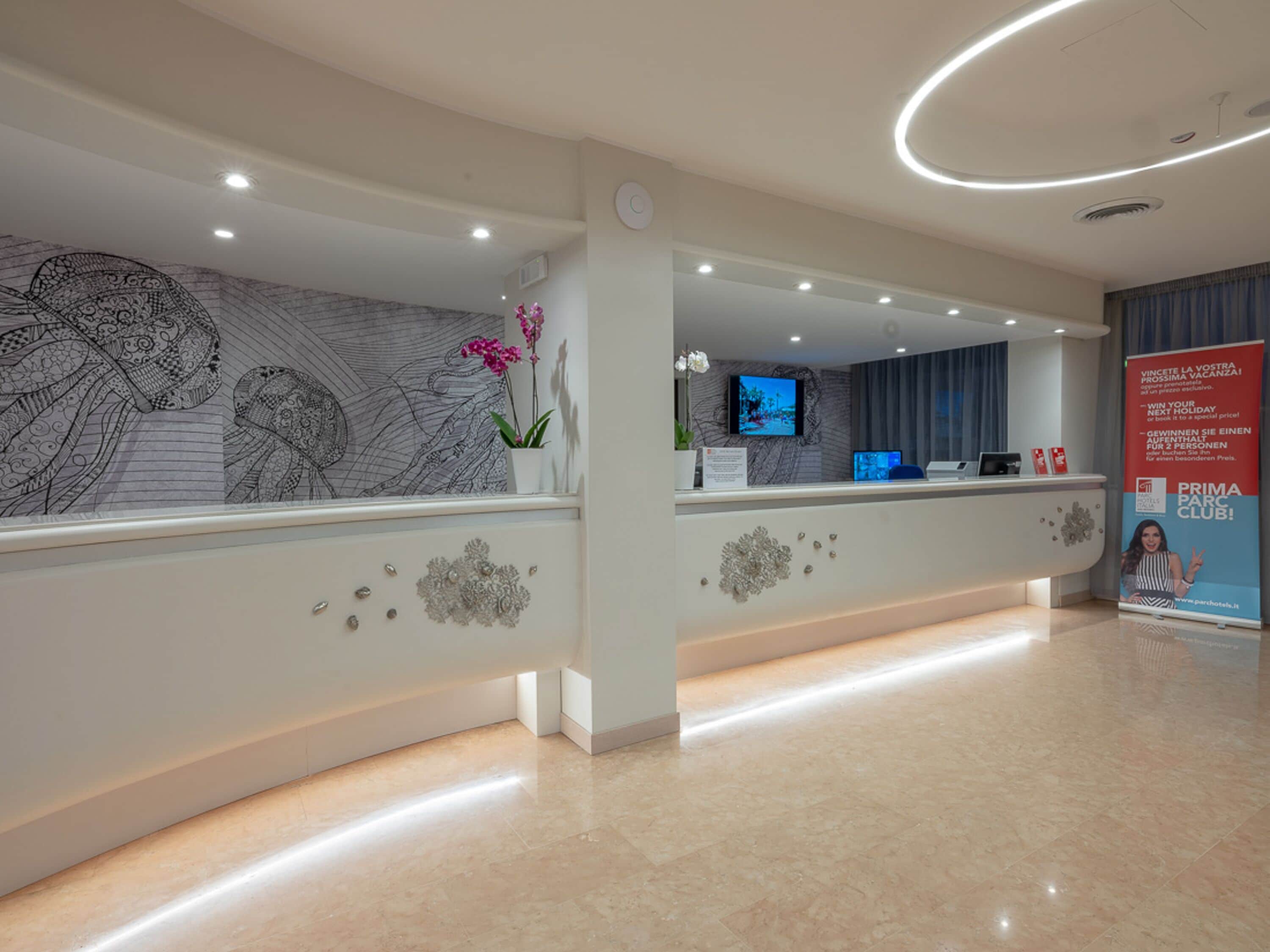 A modern reception area with a marble floor, a reception desk, a digital screen, and a decorative wall with a large black and white mural.