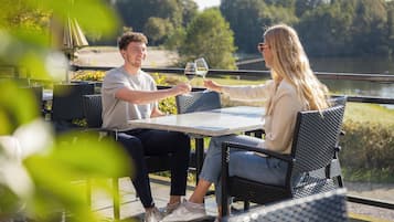 Dos personas sentadas en una mesa al aire libre con vista a un lago.
