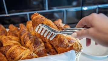 Una cesta de cruasanes siendo recogida con pinzas.