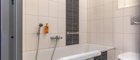 A modern bathroom with a bathtub, a toilet, and a shower.